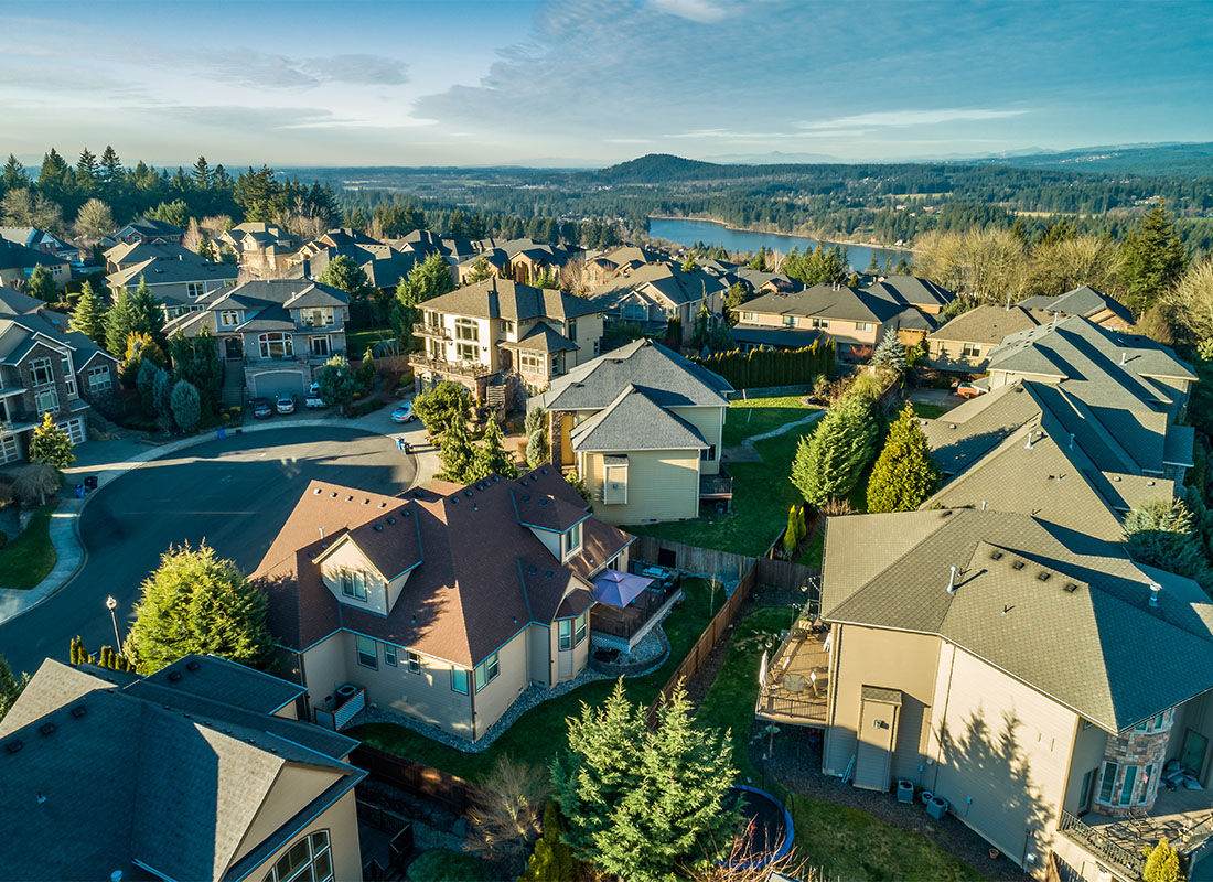 Contact - Aerial View of a Wealthy Neighborhood with Luxury Multi Story Homes Near the Lake Surrounded by Green Trees at Sunset