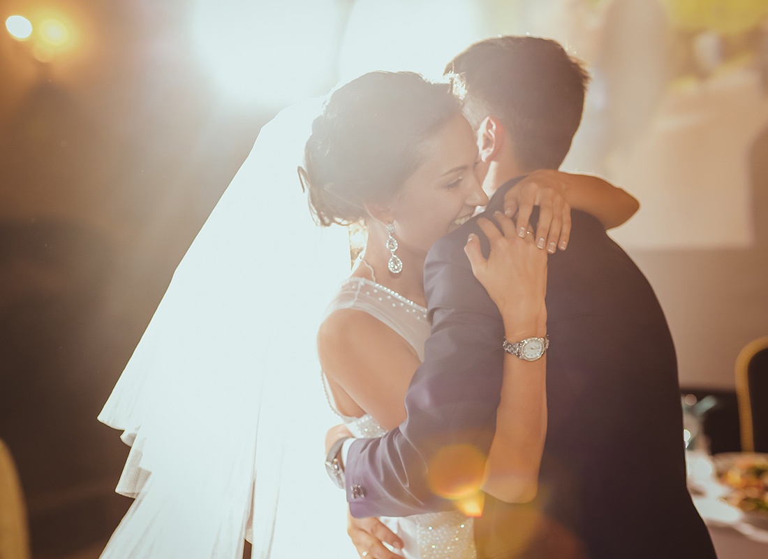 Wedding Insurance Quote - Portrait of a Happy Bride and Groom Surrounded by Warm Light Hugging Each Other During Their Wedding Reception